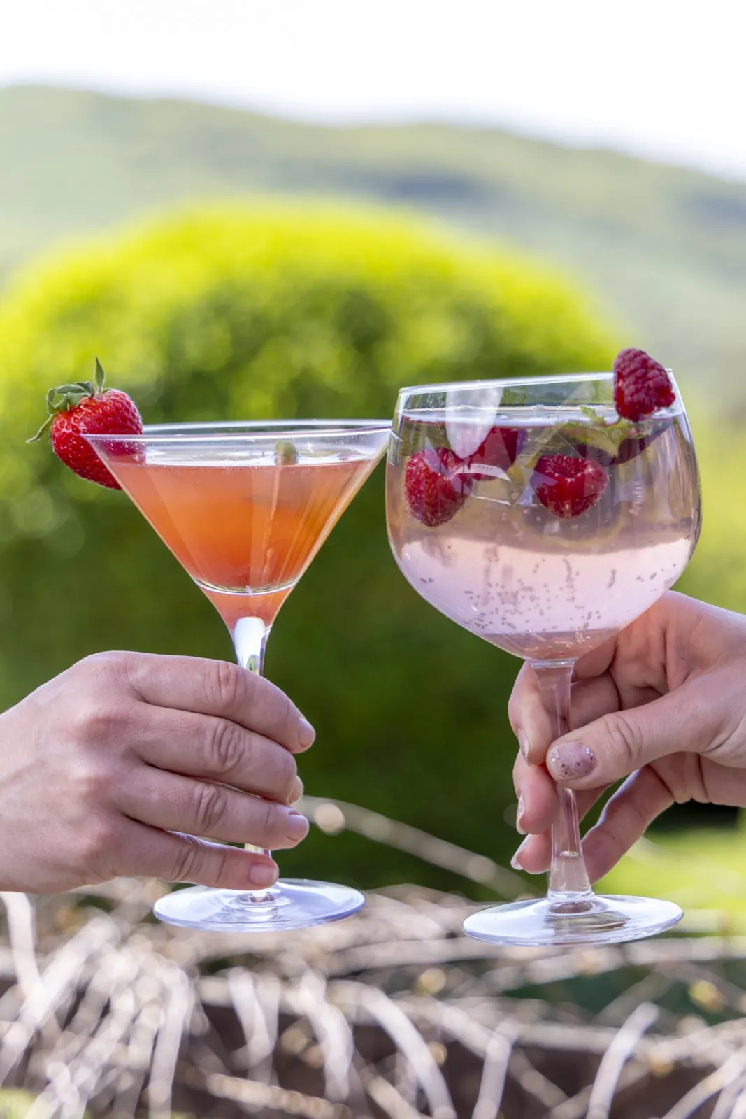 Zwei rosa Cocktails mit Himbeeren beim Anstoßen