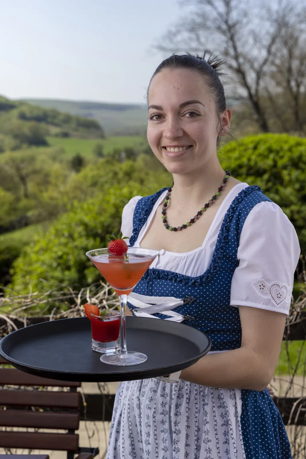 Frau im blau-weißen Dirndl mit Tablett und zwei Getränken